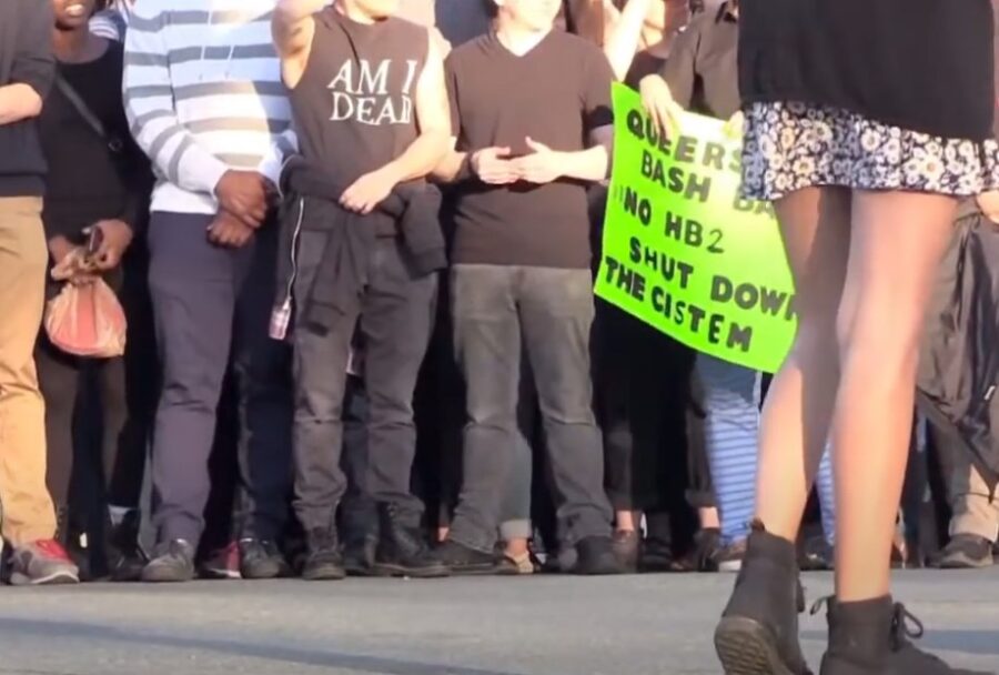 A protestor holding green LGBT sign of support