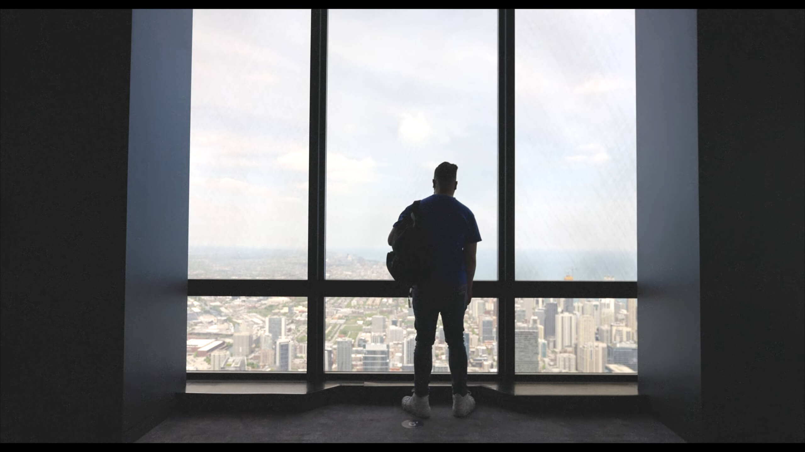 A photo of a man on the Skydeck at Willis Tower looking at the skyline of Chicago