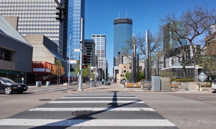 A crosswalk in Minneapolis with cars passing by and buildings visible in the background