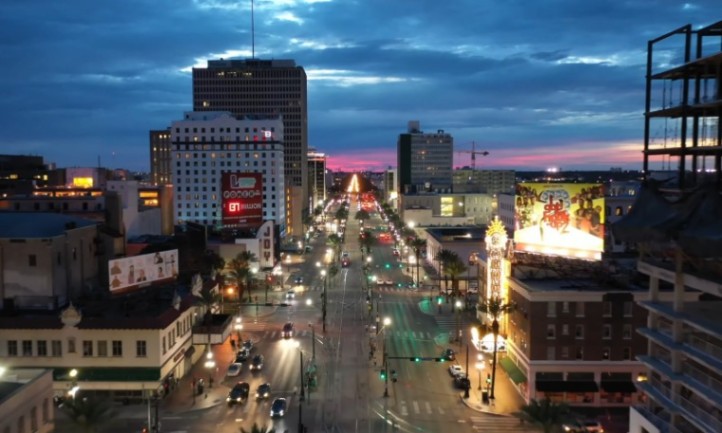 A New Orleans city street at dusk, featuring traffic lights and illuminated buildings