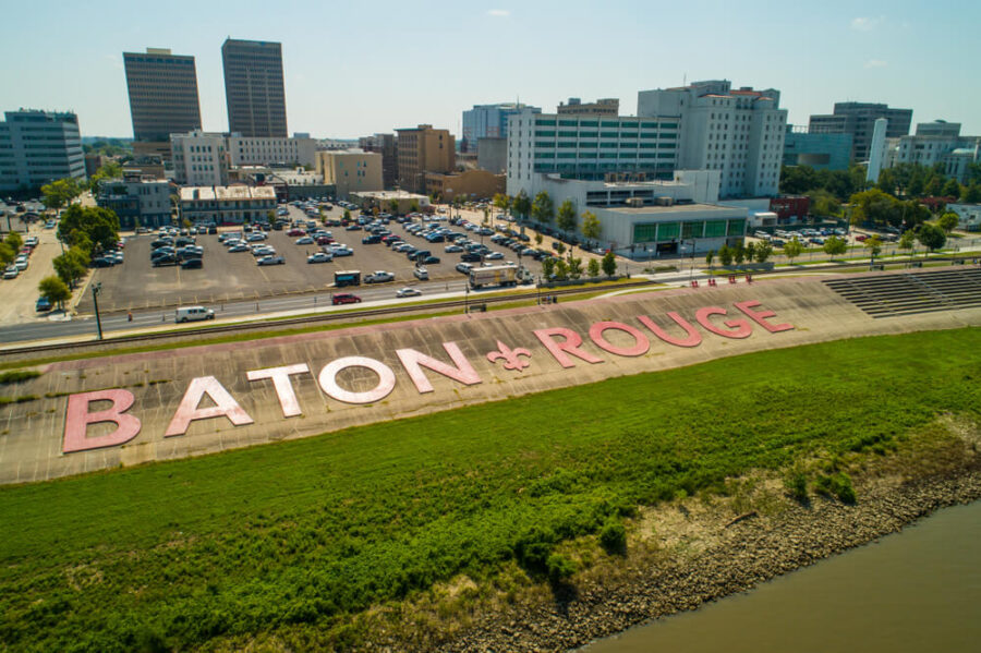 Aerial view of Baton Rouge with large pink letters spelling "BATON ROUGE" on a levee