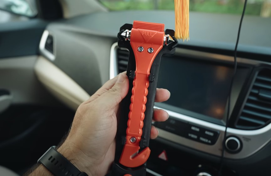 Guy holding red safety hammer in a car