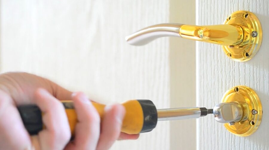 A locksmith opening the lock with a screwdriver