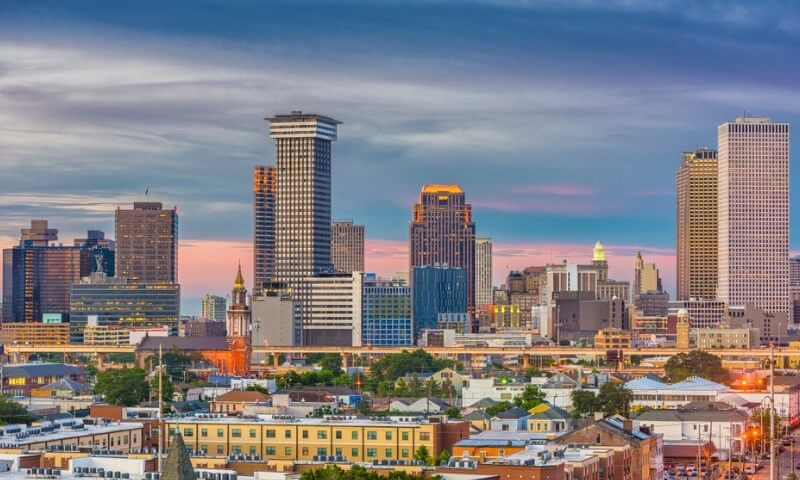 A vibrant city skyline at sunset, featuring tall buildings with varied architecture under a colorful sky