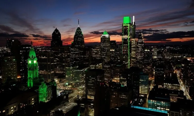 Philadelphia skyline at dusk, illuminated by green lights