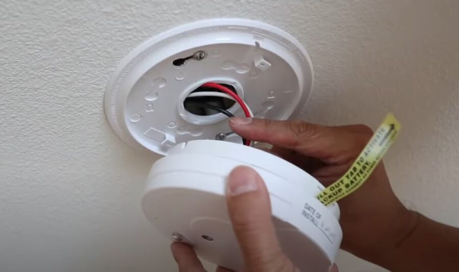 Human hand detaching fire alarm from the ceiling