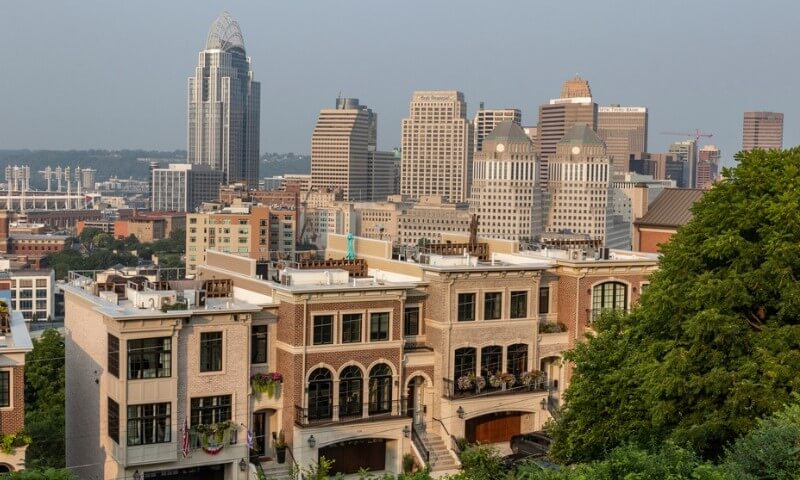 Skyline of a Cincinnati at dusk with modern skyscrapers in the background and classic brick townhouses in the foreground