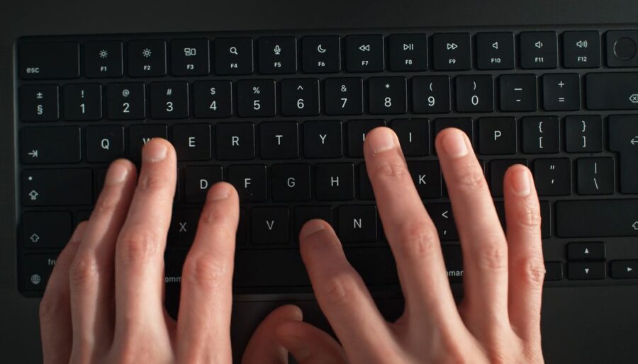 Human hands typing on a laptop keyboard