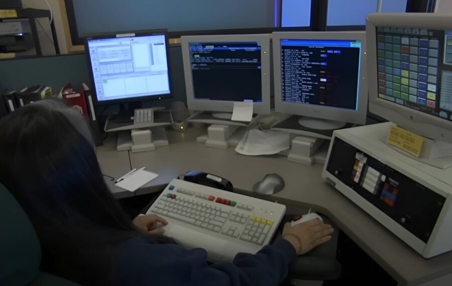 Woman working in police station surrounded by monitors