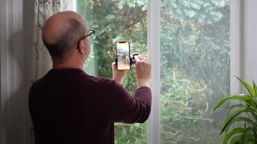 Older guy mounts iPhone camera to a window glass