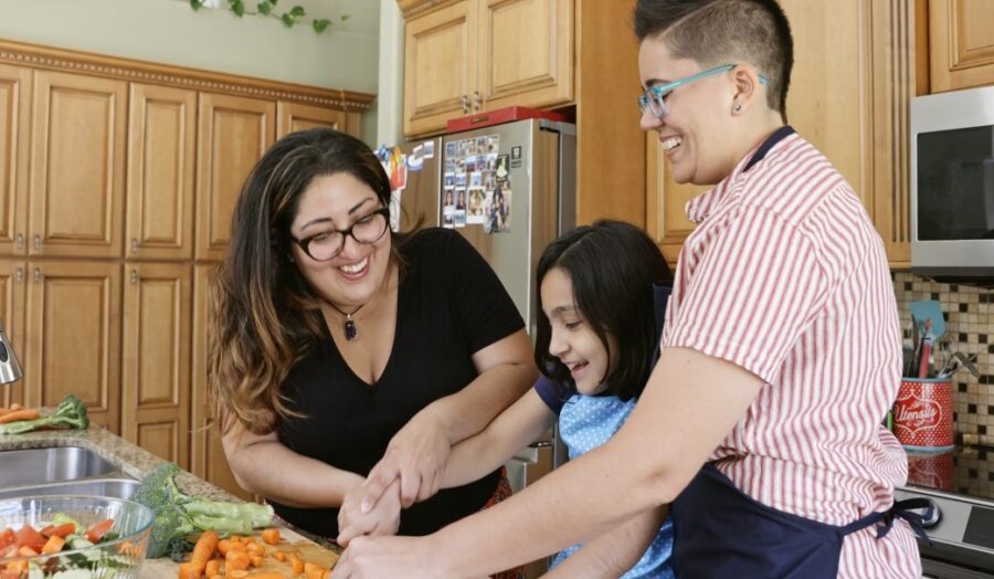 Lesbian couple making food with a child in kitchen