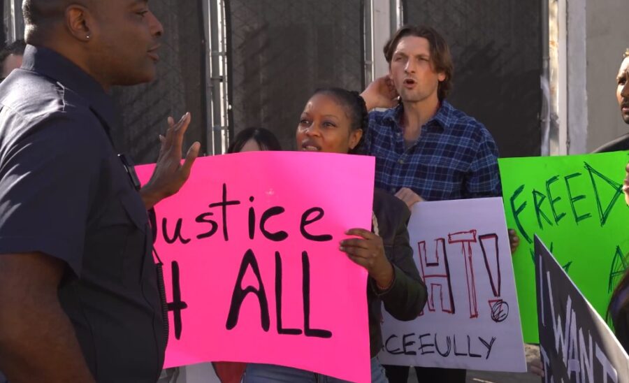 Woman protests with pink sign that says "JUSTICE FOR ALL"