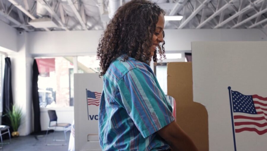 Woman casting a ballot at a voting booth.