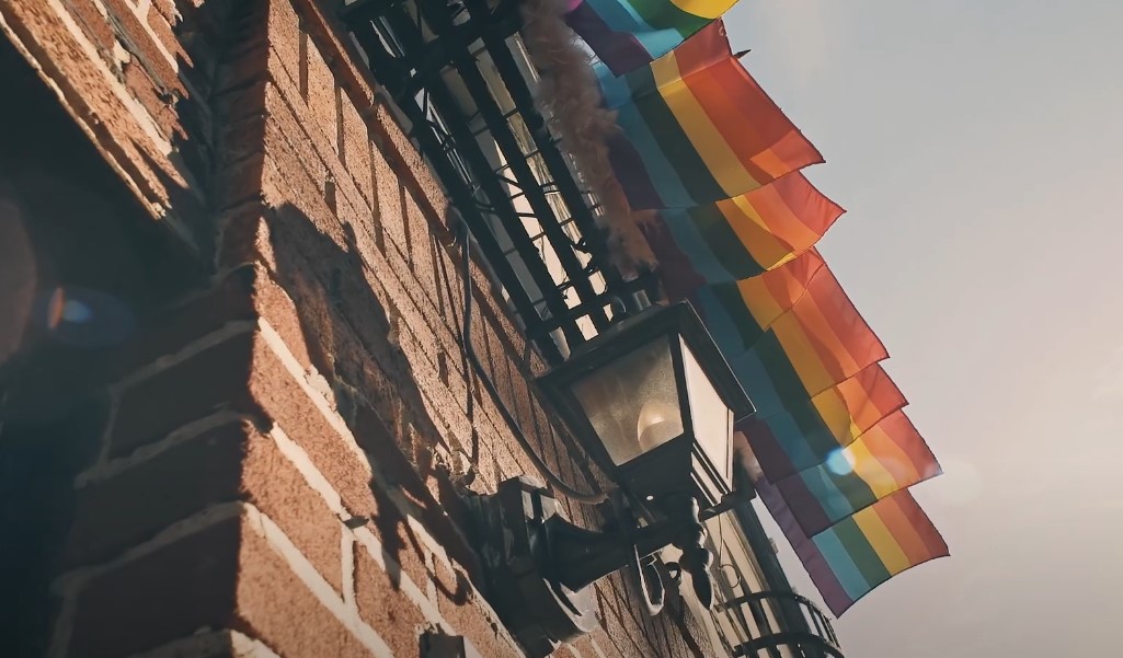 Colorful Pride flags flutter against a brick building