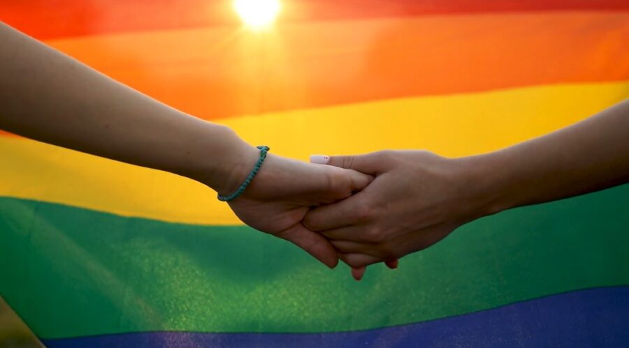 Man couple holding hands with LGBT flag in the background