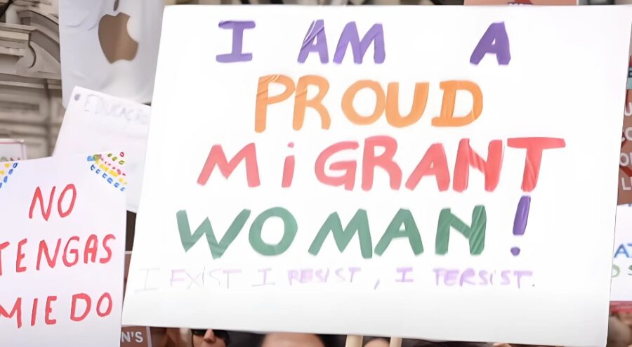 A migrant woman holding a sign on a protest