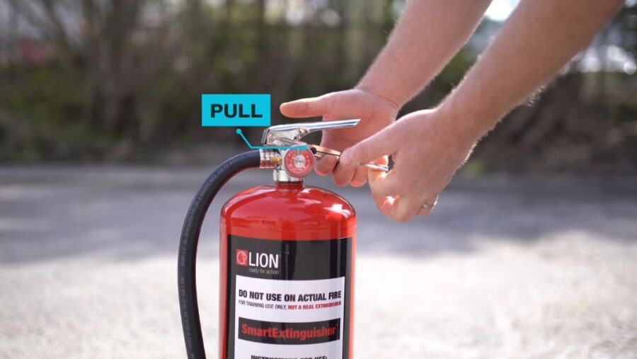 Person pulling the pin on fire extinguisher