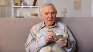 Older man counting money on a sofa