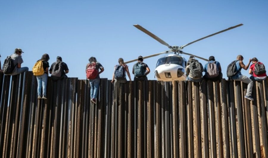 Illegal immigrants trying to enter US by climbing on a fence