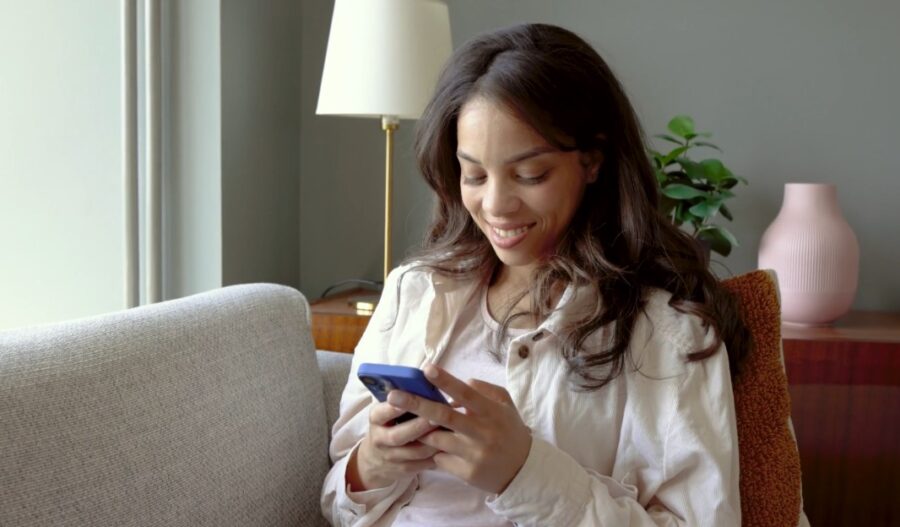 Woman engrossed in a mobile device, smiling warmly