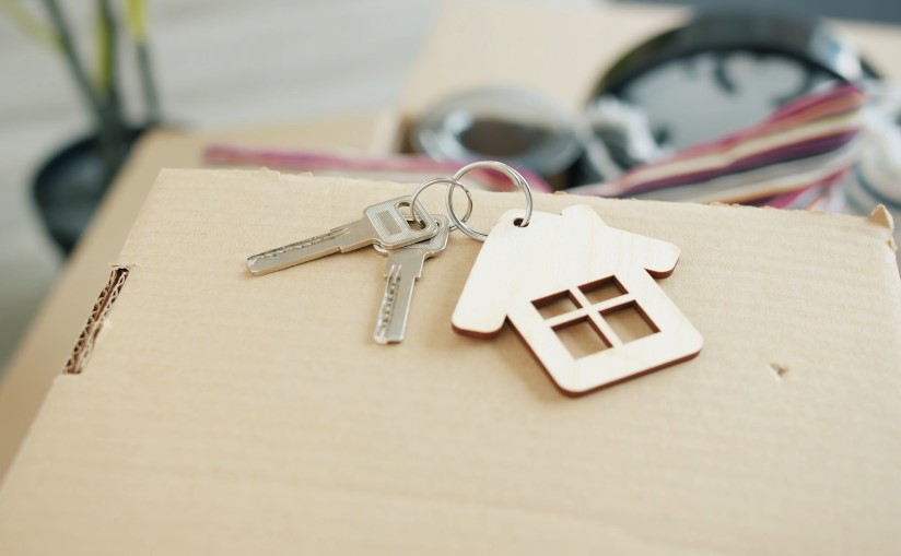 Keys and a house-shaped charm rest on a cardboard box