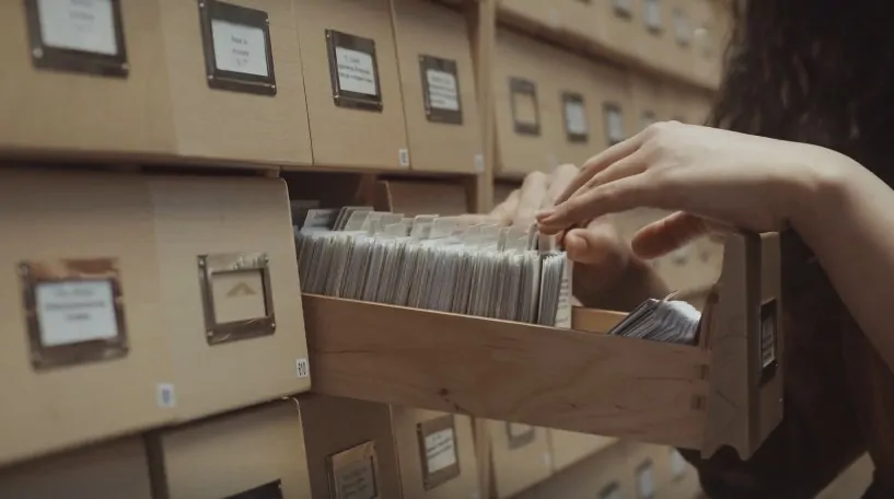 A hand reaches into a drawer, pulling out a stack of papers