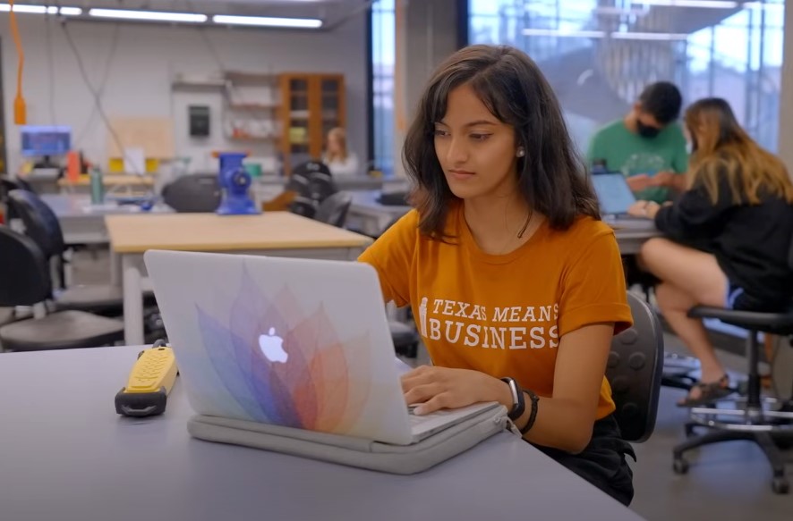 Focused student engrossed in work, laptop open on a light gray table