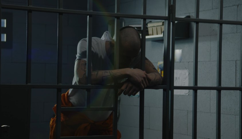 A prisoner leans against the bars