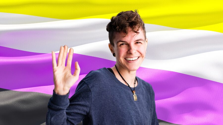 A nonbinary person, smiling and waving