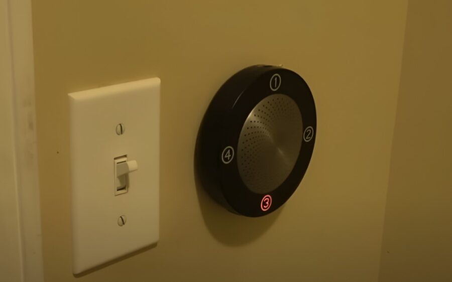 A wall-mounted audio device with numbered controls, next to a standard light switch