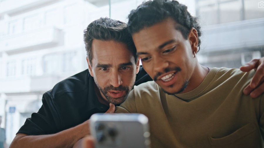 Friendly interaction between two men, focused on a mobile device