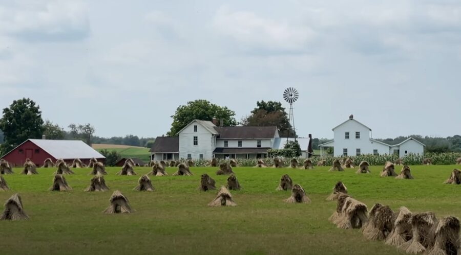 A tranquil rural scene, with weathered farmhouses and stacks of dried stalks