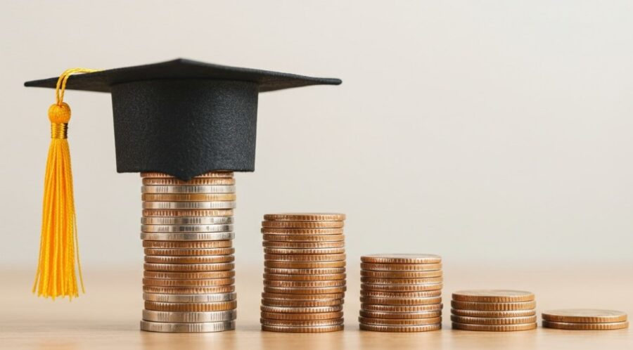 A graduation cap rests atop stacks of coins