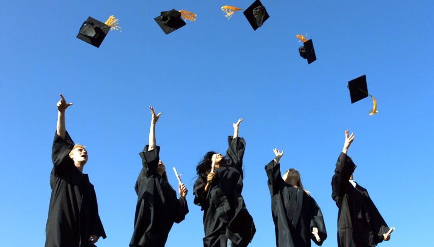 Graduates joyfully tossing their caps into the air in celebration
