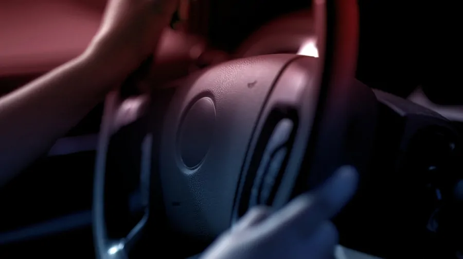 Close-up of hands on a steering wheel at night