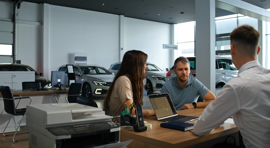 Potential buyers review contract terms in a modern dealership