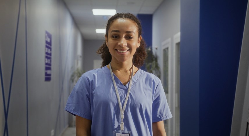 A friendly healthcare professional stands in a hospital corridor
