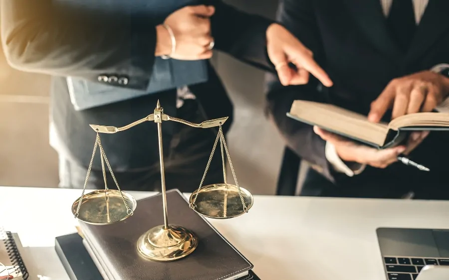 Two lawyers review legal documents next to a scale of justice, representing major personal injury settlements in U.S. history