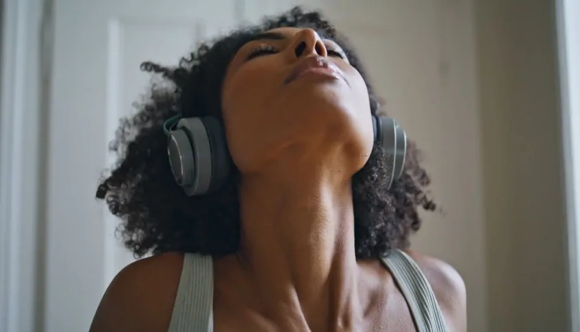 Woman engrossed in music, headphones on, head tilted back