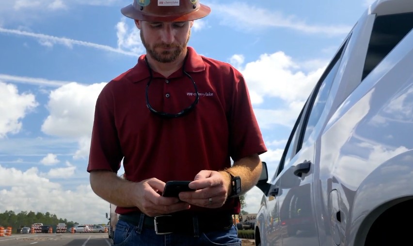 A worker consults his phone, likely reviewing project details or communicating with colleagues