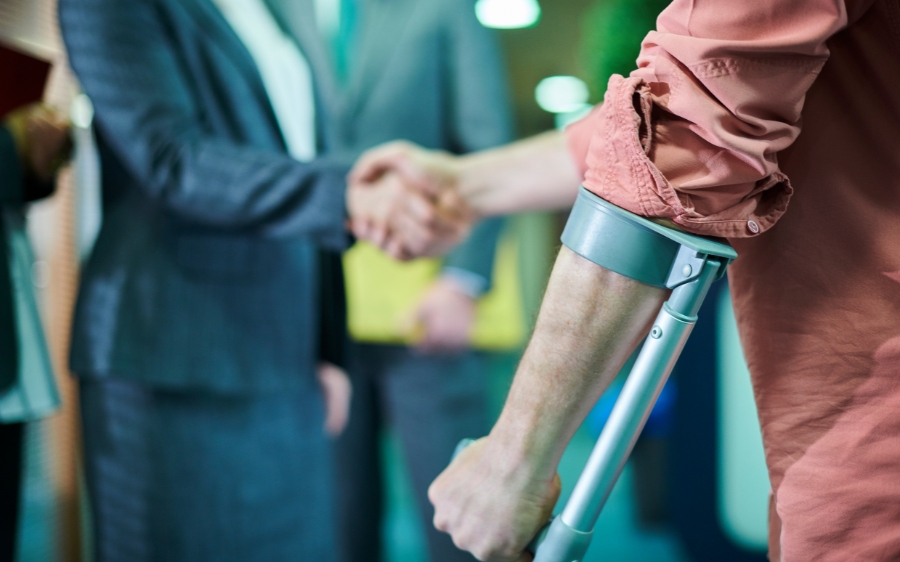 A person on crutches looks on as two people shake hands, possibly finalizing a settlement after a political rally injury