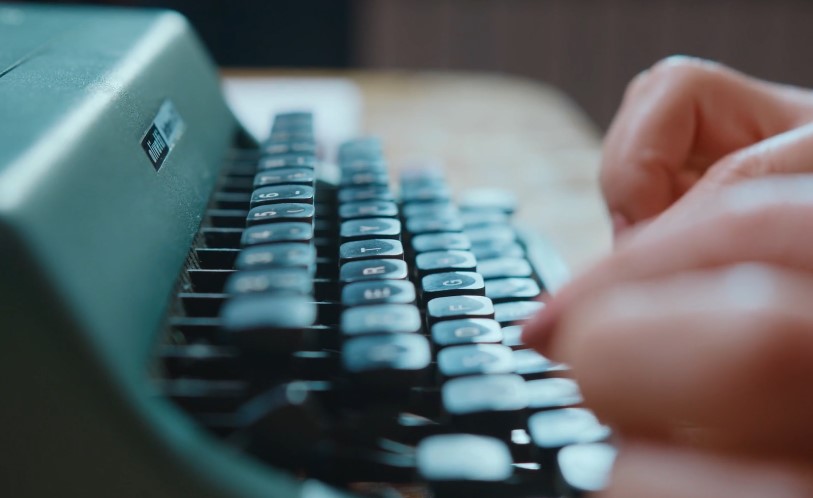 Close-up view of a vintage typewriter keyboard with hands typing
