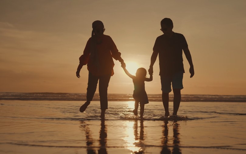 A family enjoys a peaceful sunset stroll along the shoreline