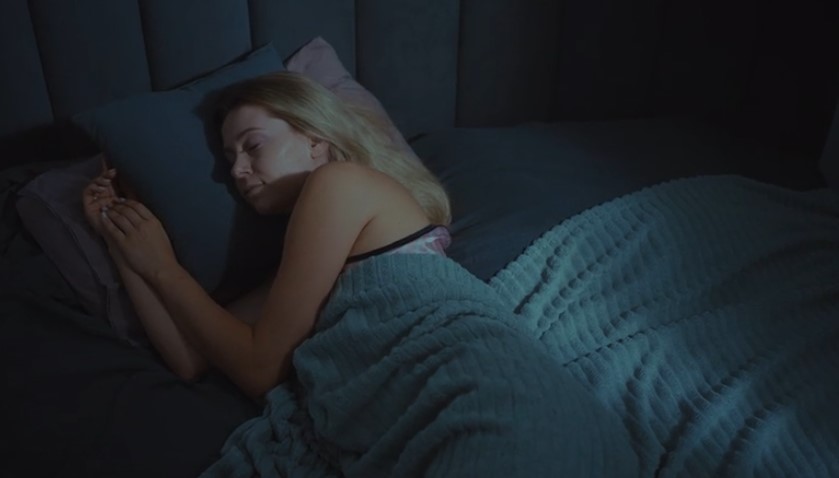 A woman rests peacefully in bed, her hands gently clasped together