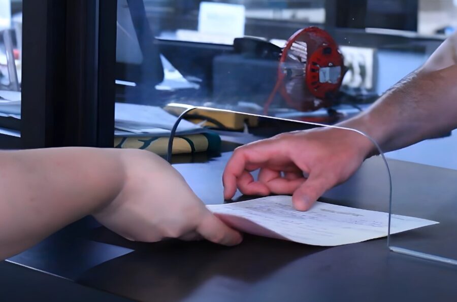Documents being exchanged across a protective barrier