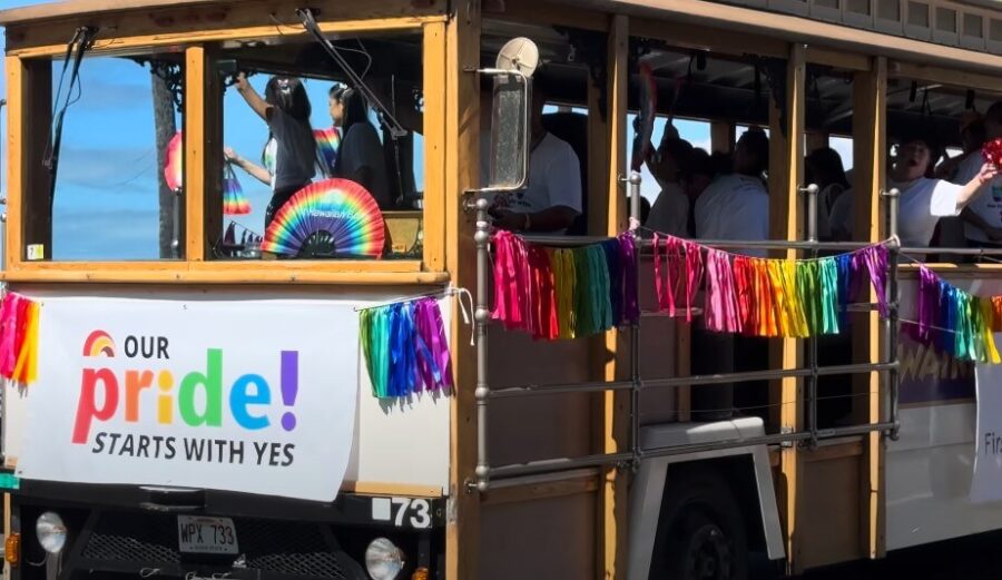 A trolley bus adorned with vibrant rainbow flags, symbolizing pride and inclusivity