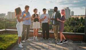 A group of friends enjoys a rooftop gathering, cocktails in hand, as the sun sets over the city