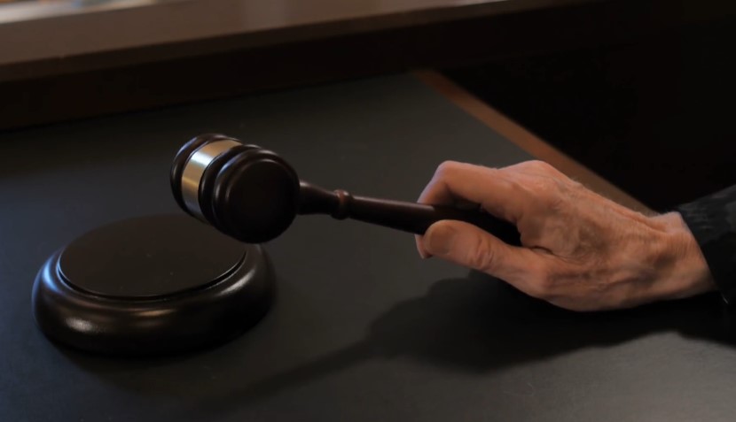 A judge's hand, poised over the gavel
