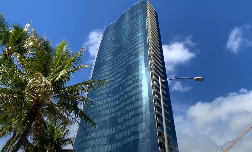 A tall building featuring a sleek blue glass facade reflecting the sky