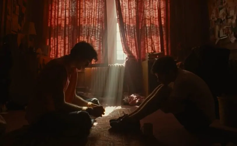 Scene from Saltburn movie, two individuals in a dimly lit room
